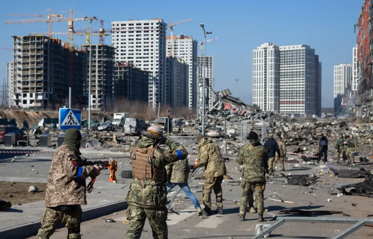 Soldats ukrainiens patrouillant dans une rue détruite après des bombardements, avec des immeubles endommagés et des gravats en arrière-plan.