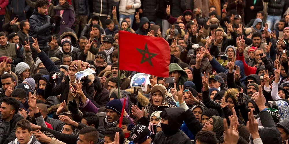 Manifestation massive au Maroc avec des jeunes brandissant des drapeaux marocains et des pancartes revendiquant des réformes sociales.