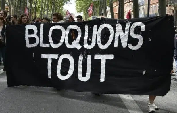 Manifestation en France avec une banderole noire où est inscrit en blanc "Bloquons tout"