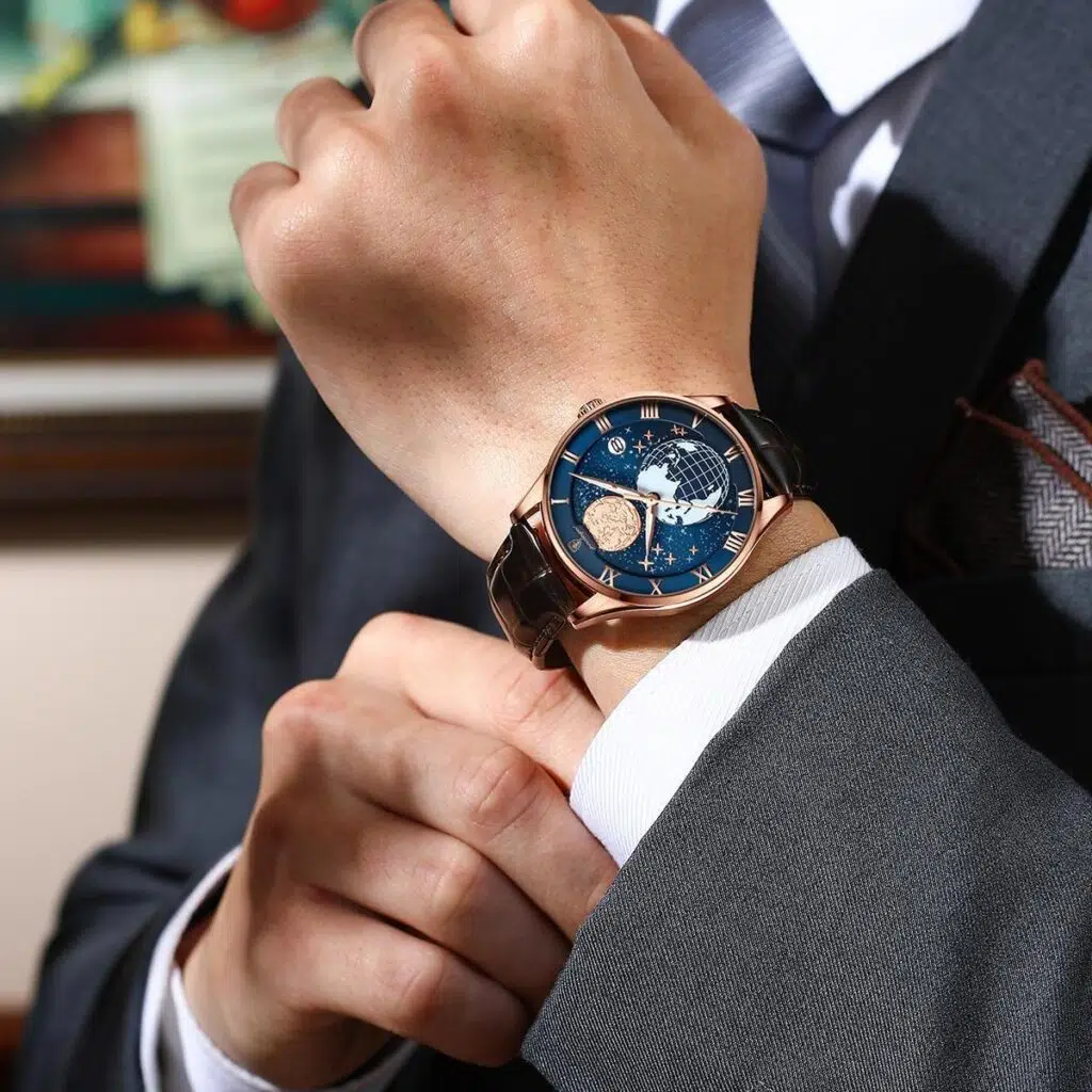 Homme en costume portant une montre de luxe mécanique avec cadran bleu étoilé et bracelet en cuir.