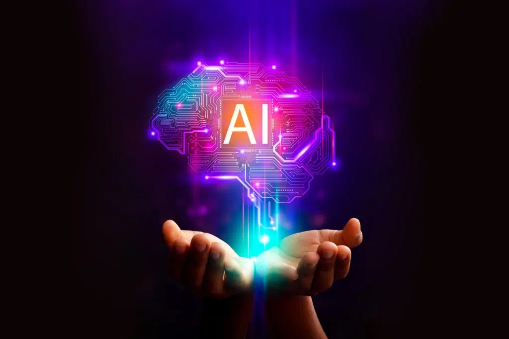 Cerveau numérique lumineux symbolisant l’intelligence artificielle, tenu dans des mains ouvertes sur fond sombre.