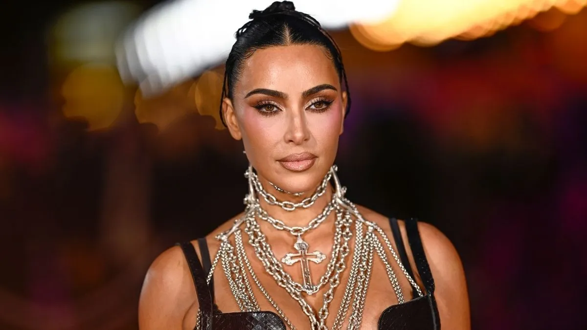 Kim Kardashian portant une robe noire et plusieurs colliers argentés superposés lors d’un événement public.