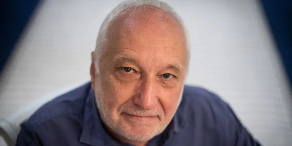 Portrait de l’acteur français François Berléand, regard direct, chemise bleue.