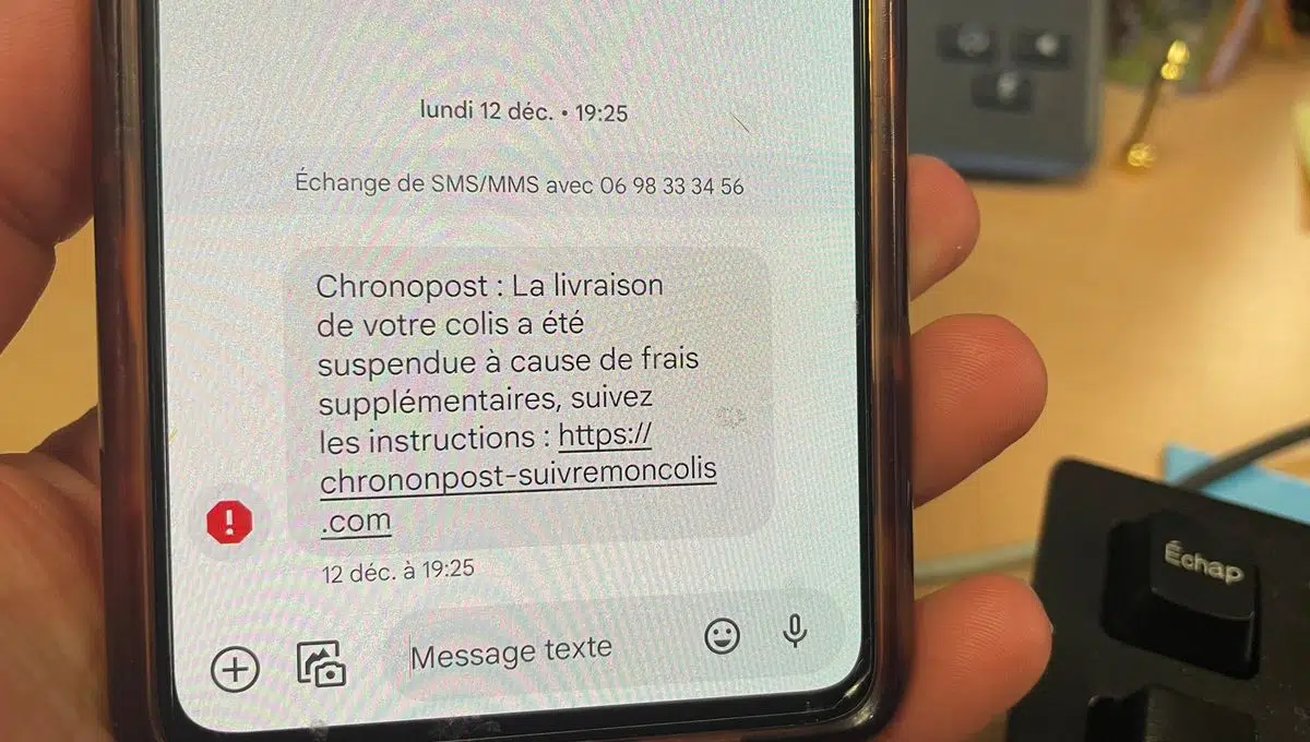 Écran de smartphone affichant un SMS se faisant passer pour Chronopost, indiquant une livraison suspendue et demandant de suivre un lien externe.
