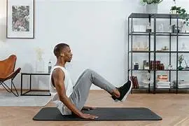Homme pratiquant un exercice de sport doux au sol dans un salon, illustrant une activité physique adaptée après 40 ans.