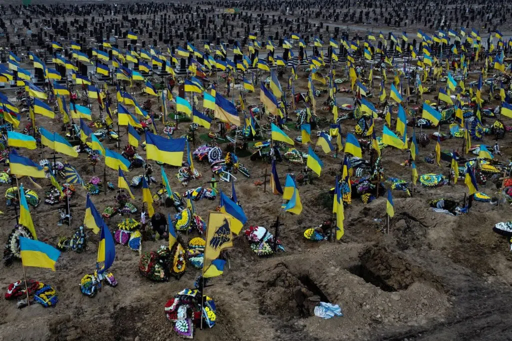 Cimetière militaire ukrainien avec des centaines de tombes marquées par des drapeaux nationaux, illustrant le coût humain de la guerre