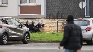 Policiers en tenue d’intervention, positionnés près d’un immeuble, lors d’une opération en zone urbaine.