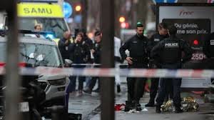 Policiers derrière un périmètre sécurisé, avec ruban de police et véhicule du SAMU en arrière-plan, de nuit.