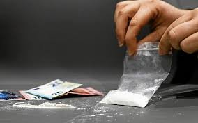 Sachet de poudre blanche et billets sur une table.