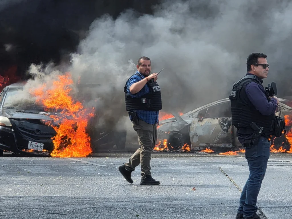 Policiers mexicains face à des voitures en flammes lors des violences après la mort d’El Mencho (CJNG), février 2026