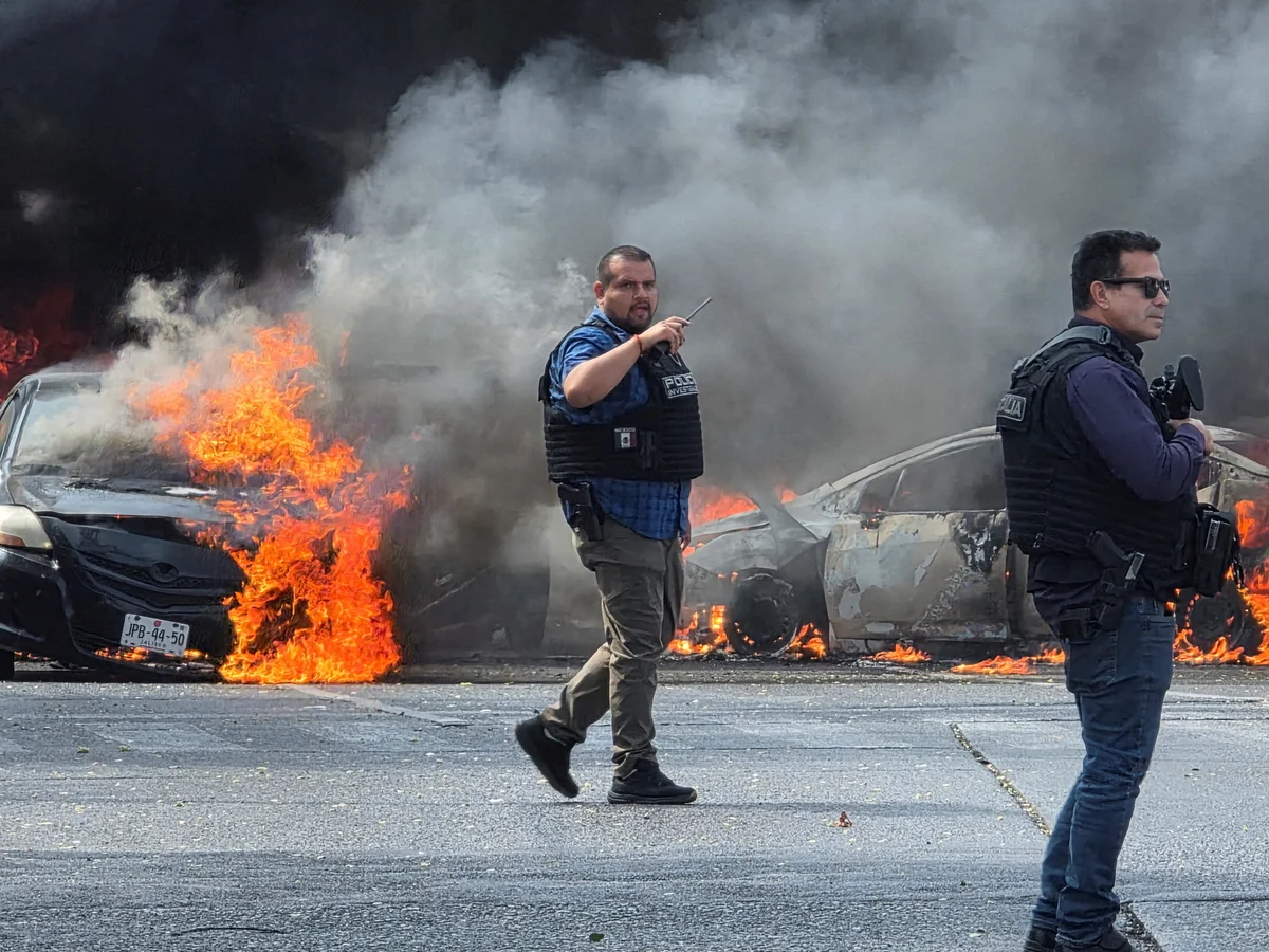 Policiers mexicains face à des voitures en flammes lors des violences après la mort d’El Mencho (CJNG), février 2026
