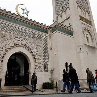 Façade d’une mosquée avec minaret et croissant, des passants devant l’entrée.
