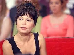 Isabelle Mergault lors d’une apparition télévisée, assise sur un canapé rouge.