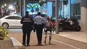 Des policiers escortent un robot humanoïde dans une rue de Macao après un incident avec une passante.