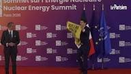 Un militant brandit une banderole sur scène lors de l’arrivée d’Emmanuel Macron au sommet mondial sur l’énergie nucléaire.