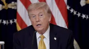 Donald Trump s’exprime lors d’une prise de parole officielle sur fond de drapeaux américains.