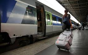 Voyageuse tirant une valise sur un quai devant un train, pour illustrer les billets de train offerts par l’Union européenne via DiscoverEU