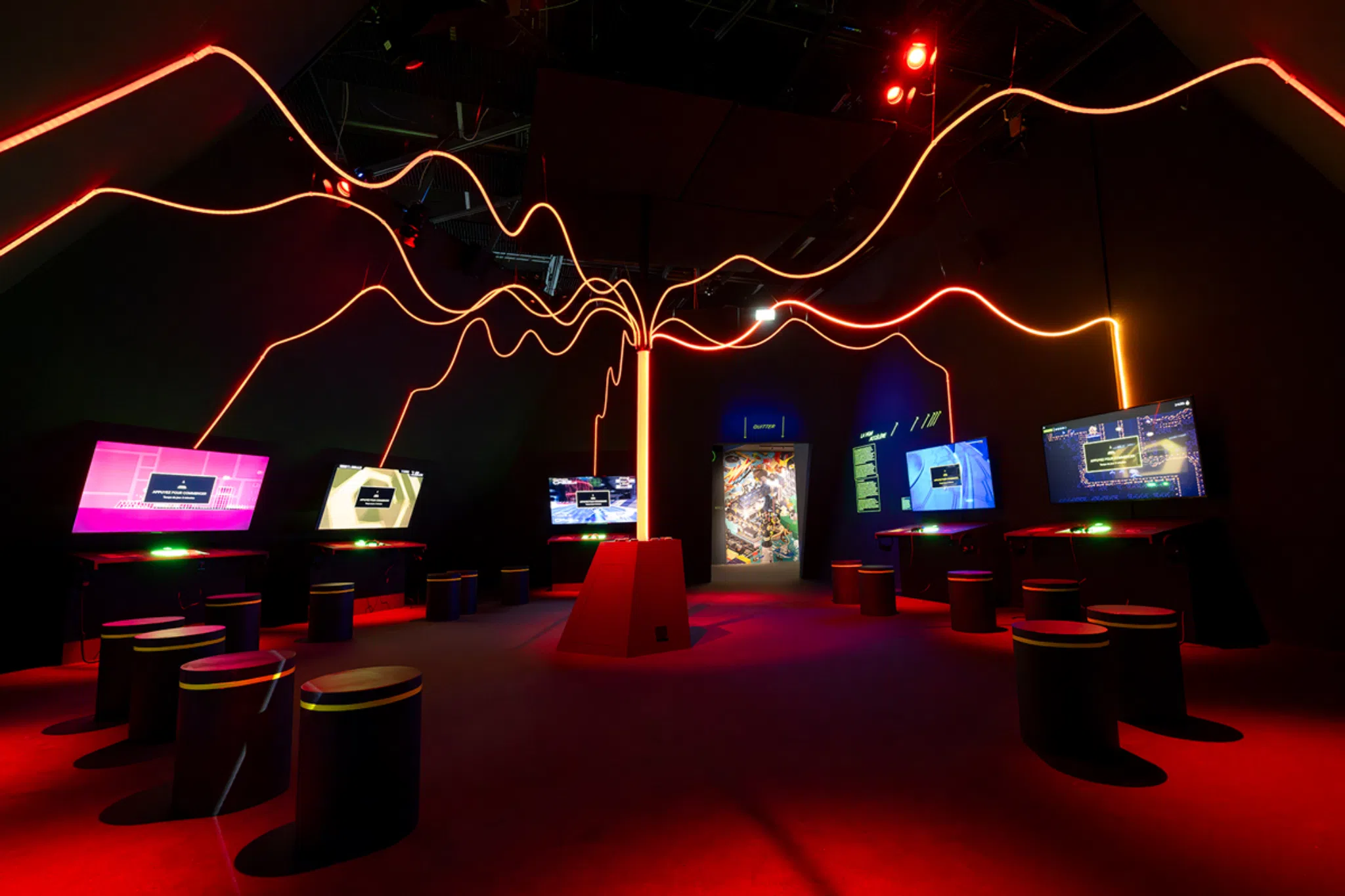 Vue d’une salle immersive de l’exposition Video Games & Music avec écrans interactifs et installation lumineuse