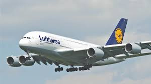 Un avion Lufthansa en vol, train d’atterrissage sorti, avec le logo jaune de la compagnie visible sur la dérive.