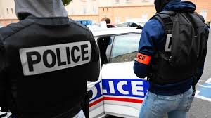 Deux policiers en civil portent des gilets Police près d’un véhicule sérigraphié lors d’une intervention.