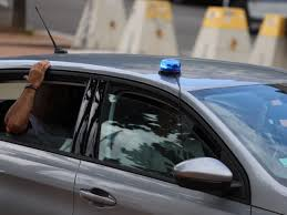 Véhicule banalisé de police avec gyrophare bleu sur le toit, vu de côté en circulation.