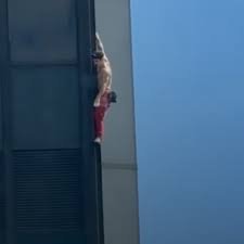 Homme suspendu à la façade de la Tour Montparnasse lors d’une spectaculaire ascension en plein cœur de Paris.