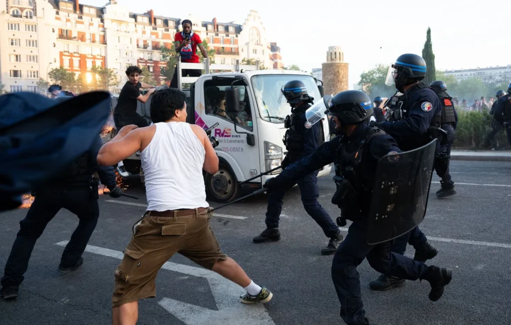 Affrontements entre des individus et des policiers équipés de boucliers après les célébrations du PSG en Ligue des champions à Paris.