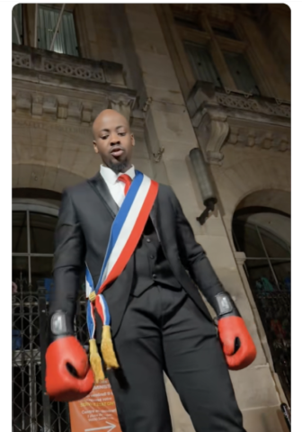 Homme portant une écharpe tricolore et des gants de boxe devant un bâtiment officiel dans un clip relayé sur les réseaux sociaux.