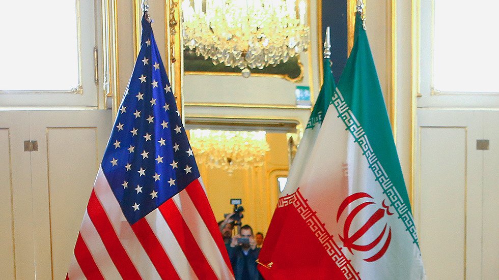 Drapeaux des États-Unis et de l’Iran côte à côte dans une salle officielle, illustrant les tensions diplomatiques entre Washington et Téhéran.