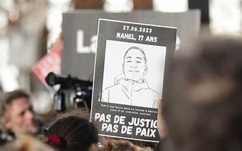 Manifestant tenant une pancarte “Nahel, 17 ans” avec le message “Pas de justice, pas de paix”, lors d’un rassemblement après la mort du jeune homme à Nanterre.