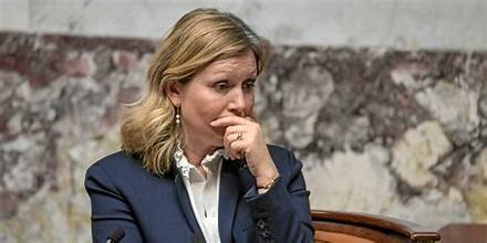 Responsable politique assise dans un hémicycle, le visage sérieux, lors d’un débat parlementaire.