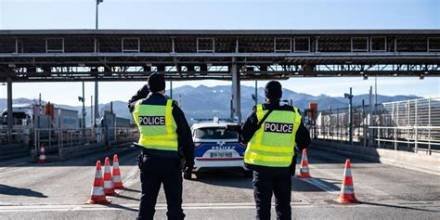 Deux policiers en gilet jaune surveillent un point de contrôle routier installé avec des cônes de signalisation à la frontière franco-espagnole.