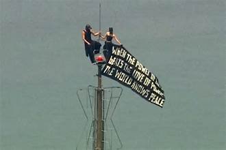 Deux personnes perchées au sommet d’une antenne de l’Empire State Building, tenant une grande banderole au-dessus de New York.