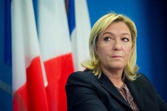 Responsable politique française devant plusieurs drapeaux tricolores lors d’une prise de parole publique.