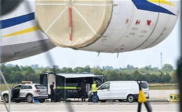 Des véhicules de police et un fourgon stationnés sous un avion-cargo à l’aéroport de Leipzig/Halle après la découverte d’un drone suspect.