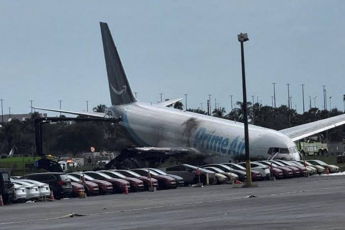 Avion-cargo Amazon Prime Air immobilisé après sa sortie de piste à l'aéroport de Miami, près de plusieurs véhicules.