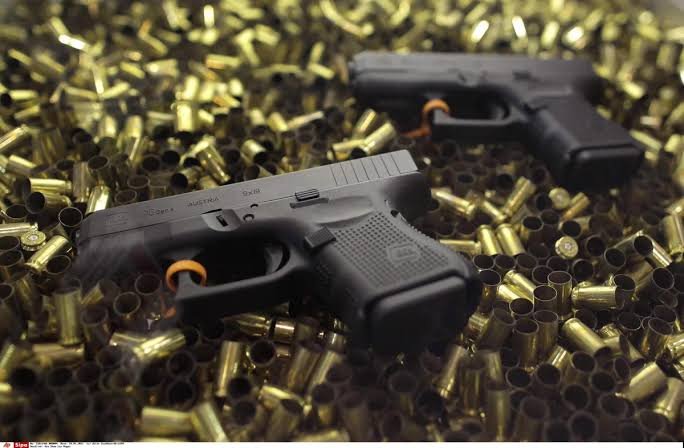 Deux pistolets posés parmi de nombreuses munitions, illustrant une saisie d’armes dans le cadre d’une affaire de trafic.